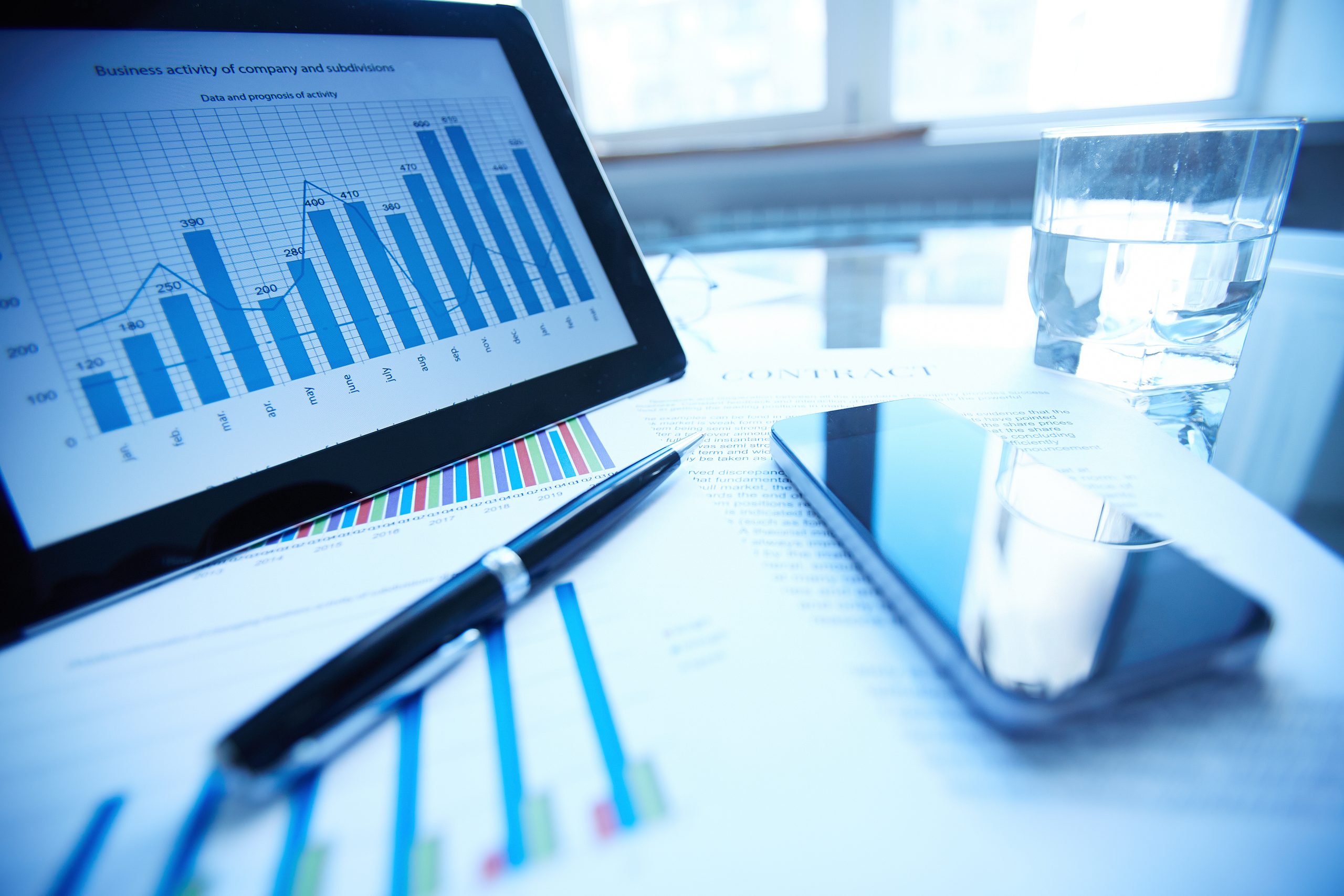 Image of documents, pen, cellular phone, glass of water and touchpad on workplace